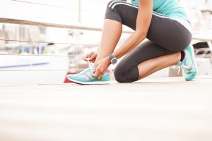 Young girl tying her shoe laces before enjoying a morning run at sunrise