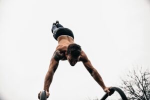 Man with doing handstand on bars with strong shoulders