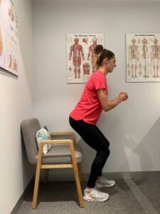 Woman beginning to stand from a seated position in chair