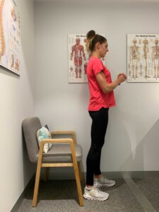 Woman stands upright after completing a sit-to-stand exercise